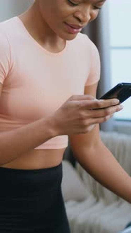 Smiling Woman Uses Phone on Treadmill at Home