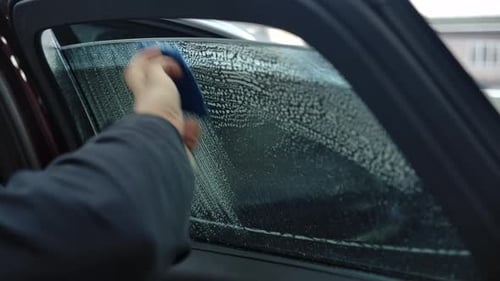 Hand Wipes Car Window with Soapy Blue Cloth