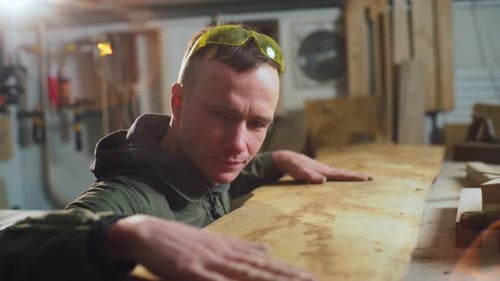 Manual Labor Worker Carpenter in a Repair Shop with His Hand Checks the Quality of Wood Processing
