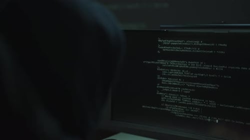 Rückansicht eines unbekannten Hackers mit Kapuze, der bösartigen Code auf dem Computerbildschirm eingibt und zugreift