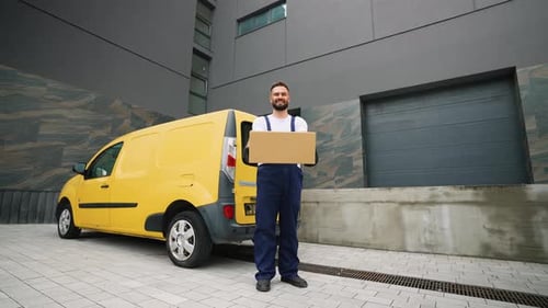 Delivery Man Holding Cardboard Box Near Yellow Van