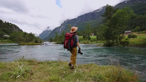 Une touriste photographe au chapeau prend des photos de la nature dans les montagnes