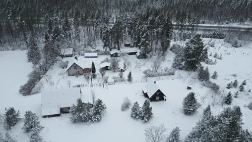 Stunning Aerial View of Cozy Cabins Blanketed in Snow Perfectly Nestled in a Picturesque Winter