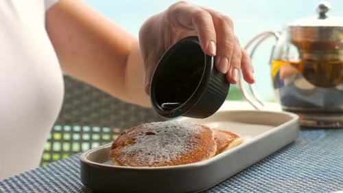 Woman Pouring Maple Syrup on Pancakes on Breakfast