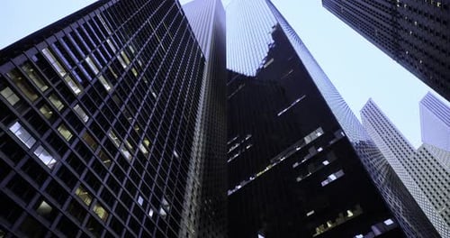 Vista hacia el cielo de imponentes rascacielos al anochecer en una ciudad moderna