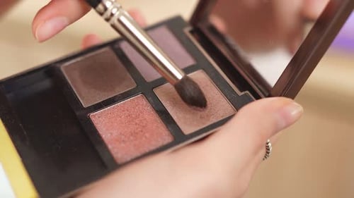 Mulher maquiadora profissional aplicando maquiagem com uma paleta nas mãos