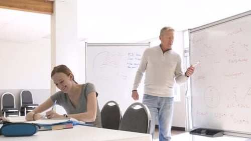 High School Student Watching Teacher at Whiteboard in Classroom Adult
