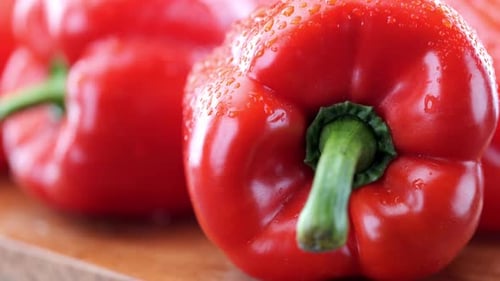 Fresh red pepper on wooden chopping board, extreme close-up pan