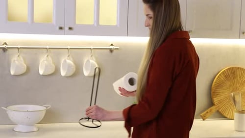 Woman using paper towels at white marble countertop in kitchen