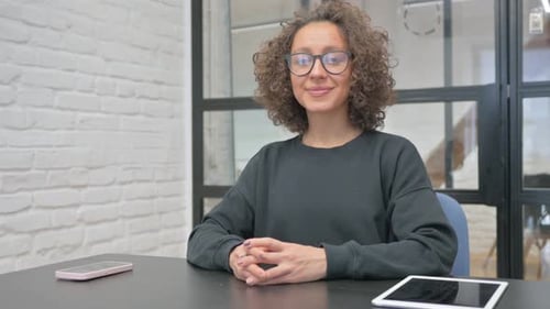 Woman Smiling at Table with Devices