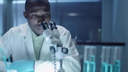Científico afroamericano usando un microscopio en el laboratorio