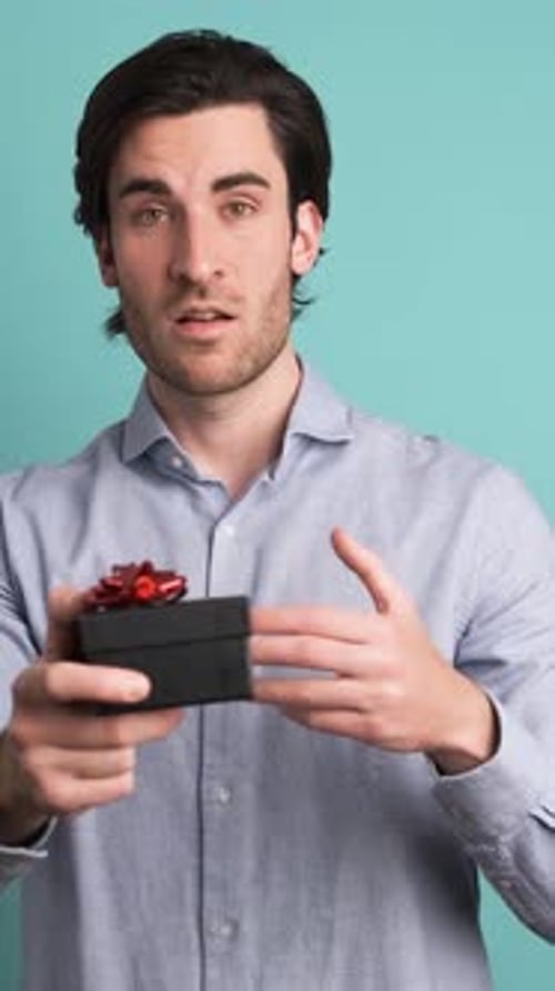 Happy Adult Man Receiving Gift Box in Blue Studio