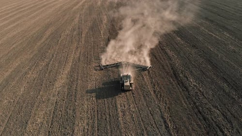 Agricultural Tractor with Cultivator Rides on Field and Loosens Dry Land and Creates Lot of Dust