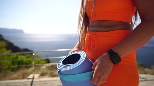 Woman Yoga Nature Healthy Happy Lady in Orange Outfit Stands on Cliff Overlooking Sea Ocean Holding