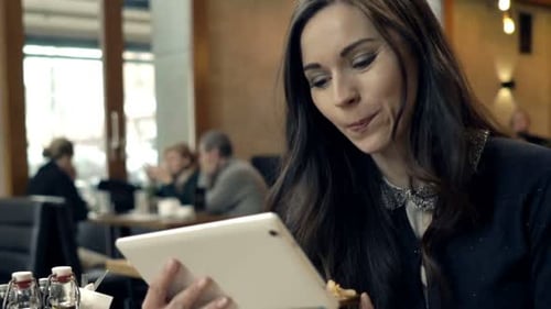 Happy, Young Woman Watching Movie on Tablet During Meal in Cafe 30s