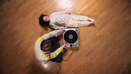 Child Lying Down While Young Man Plays Record