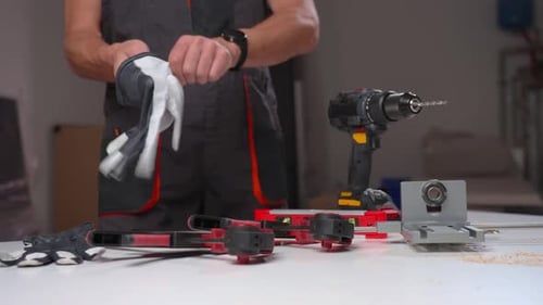 Man Putting on Safety Gloves in Workshop
