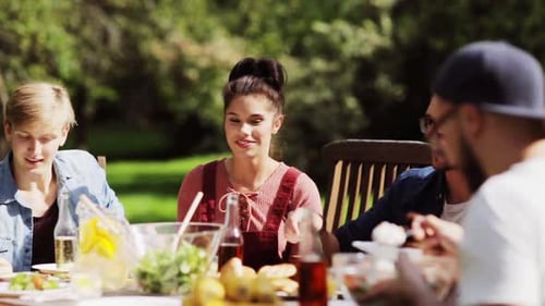 Leisure, Holidays, Eating, People And Food Concept - Happy Friends Having Dinner At Summer Garden...