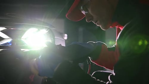 Auto Detailer Buffs Car Headlight at Night