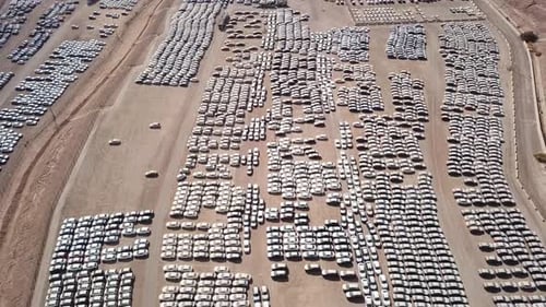 New cars covered in protective white sheets parked in a holding platform