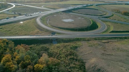 Neigbare Luftaufnahme der Autobahnkreuzung mit dem Autoverkehr, der Autobahn inmitten grüner Bäume und