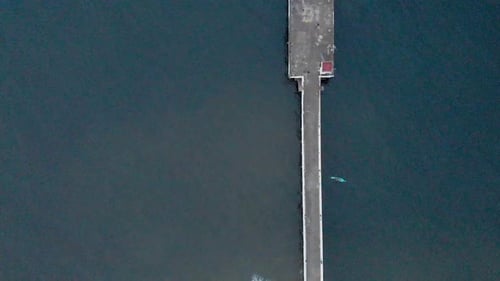 4k Aerial Top Down Pull Up shot of a Shipping Port Pier on a Sunrise with monsoon clouds covered nea