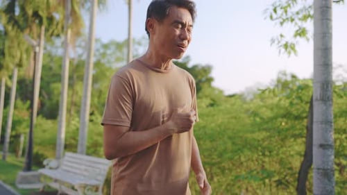 Asian senior elderly man feel pain heart attack while exercise in garden.