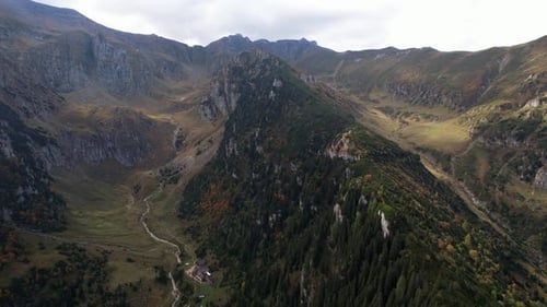 Autumn colors drape the Bucegi Mountains, aerial view of rugged peaks and valleys