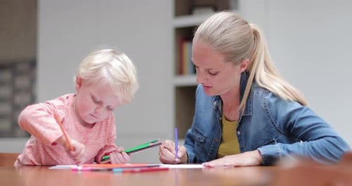 Woman and child coloring together indoors at table