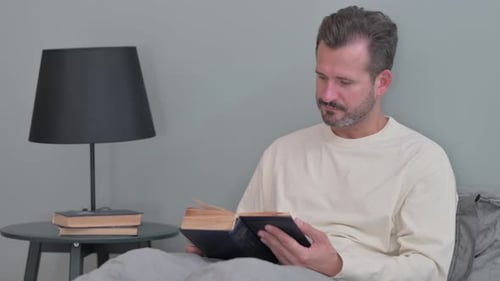 Man Reading a Book in Bed