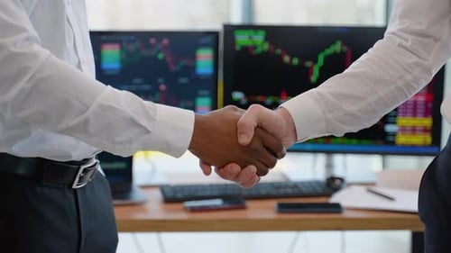 Close Up of Two Diverse Traders Handshake with Candlestick Forex or Cryptocurrency Chart on Blurry