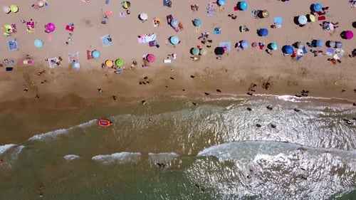 Bird's eye view of colorful tourist umbrella in the beach with sea waves