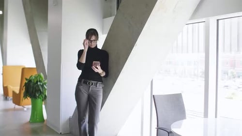 Businesswoman texting on smart phone inside modern office building portrait