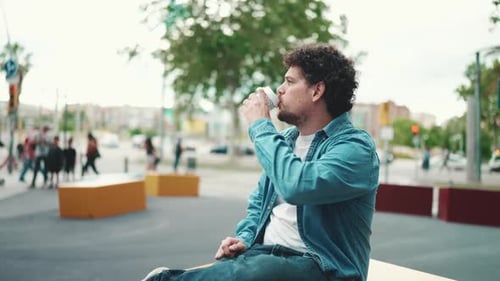 Clouse-up, man sitting and drinking coffee on busy street on modern city background