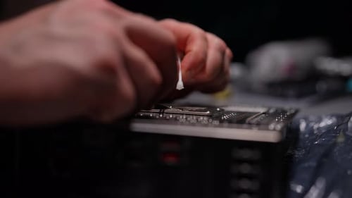 Closeup Hand of Skilled Computer Technician Carefully Removing Residual Thermal Paste From CPU