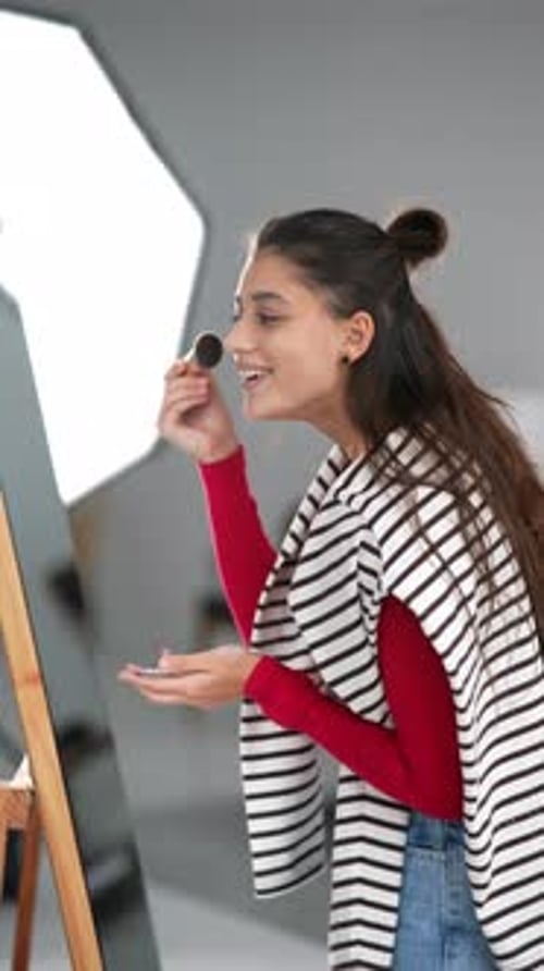 Young Woman Applying Makeup in Front of Mirror