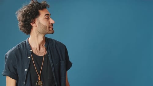 Surprised man looks to side to show copy-space isolated on blue background in studio