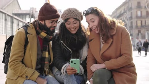 Three Young Adults Looking at Smartphone in City