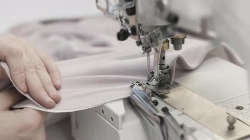 Skilled Hands Use a Sewing Machine in a Textile Workshop to Stitch Fabric with Precision
