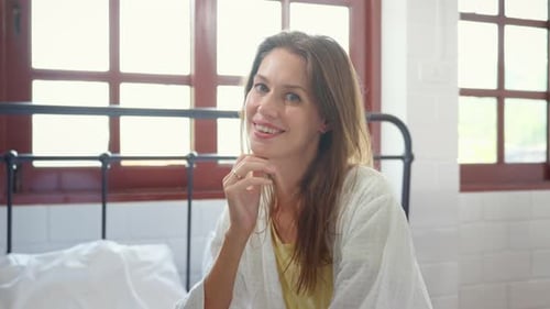 Woman Smiling and Sitting in a Bedroom