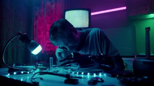 Young Adult Working on Robotics Arm in Dimly Lit Room