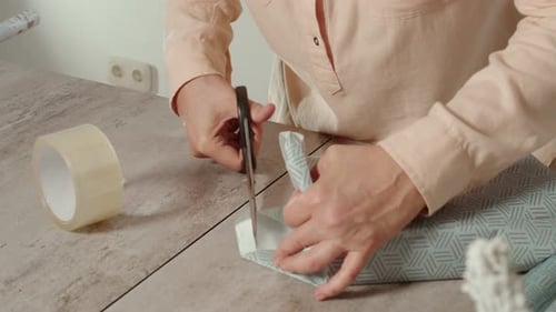 Woman wrapping present with patterned paper at table