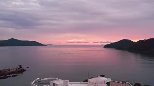 Dramatisch Sonnenuntergang. Rückwärts fliegende Luft enthüllt Herrenhaus auf der felsigen Küsteninsel