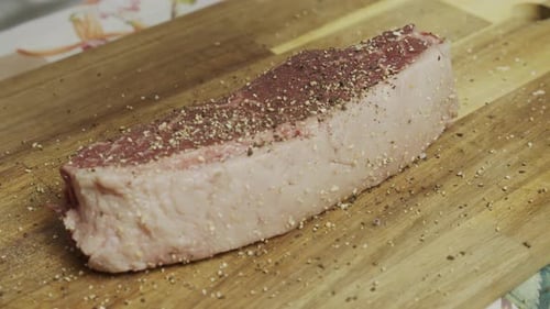 Adding spice onto meat steak on cutting board. Slow motion close up shot.