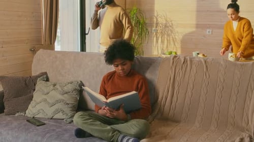 Boy Reading Book on Couch at Home