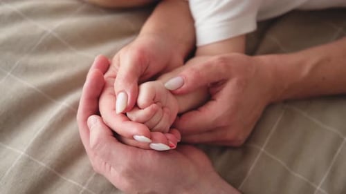 Parents Holding Tiny Hand of Infant Child