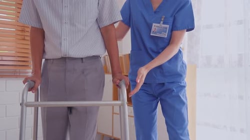 Senior Man Walks with Assistance from Caregiver