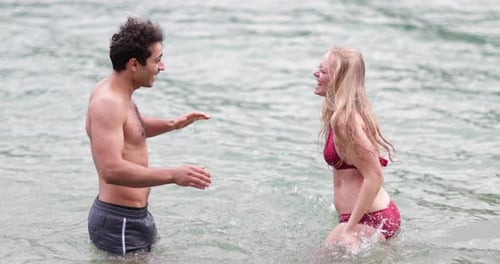 Couple splashing each other with water