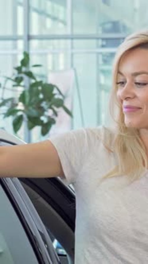 Smiling Woman Leans Against New Car in Showroom