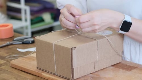 Woman Tying a Box with String Close Up